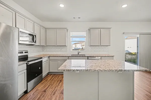 a kitchen with granite countertop a sink stainless steel appliances and cabinets