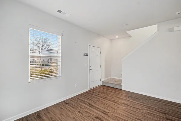 a view of an empty room with wooden floor and a window