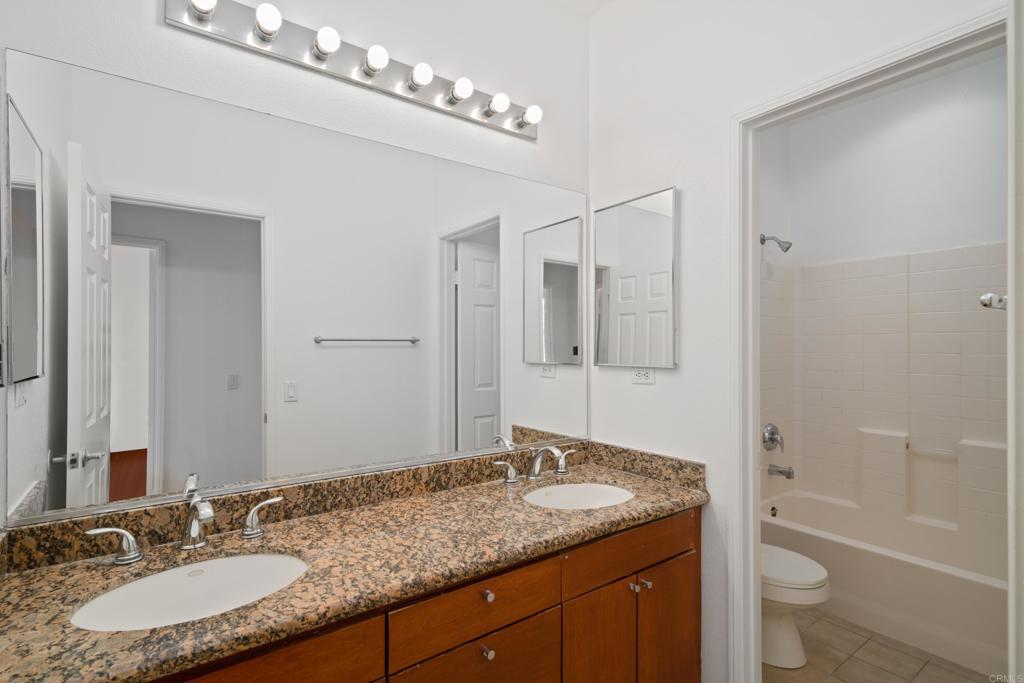 1917 Lagrange Road Chula Vista, CA 91913 - Photo 23 of 36 a bathroom with a granite countertop sink a toilet a mirror a bathtub and shower