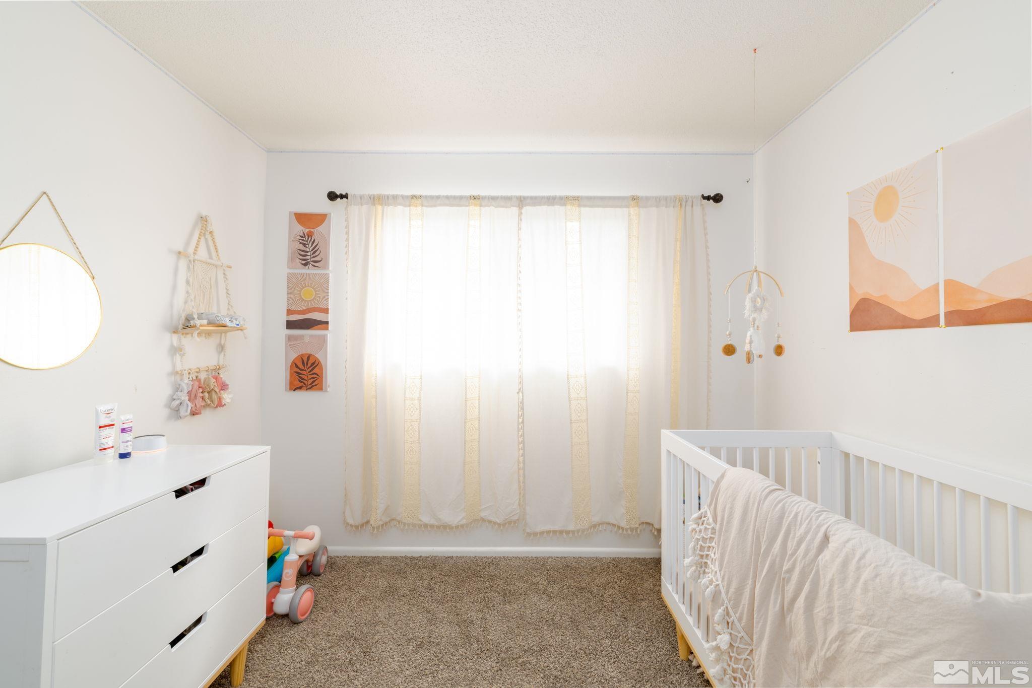 2400 Apollo Way Reno, NV 89503 - Photo 23 of 30 a bedroom with a baby bed a couch and a window