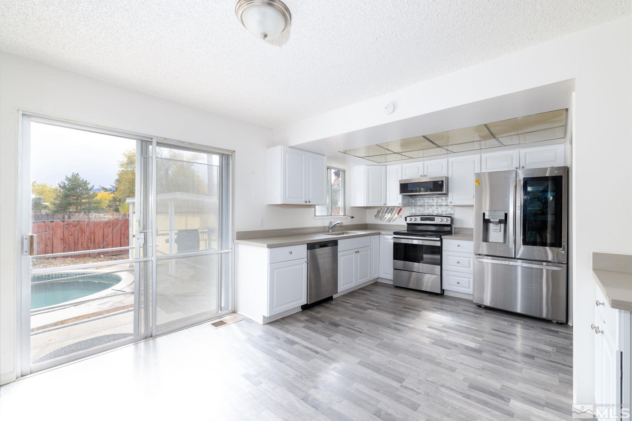 2400 Apollo Way Reno, NV 89503 - Photo 10 of 30 a kitchen with granite countertop stainless steel appliances refrigerator sink and microwave