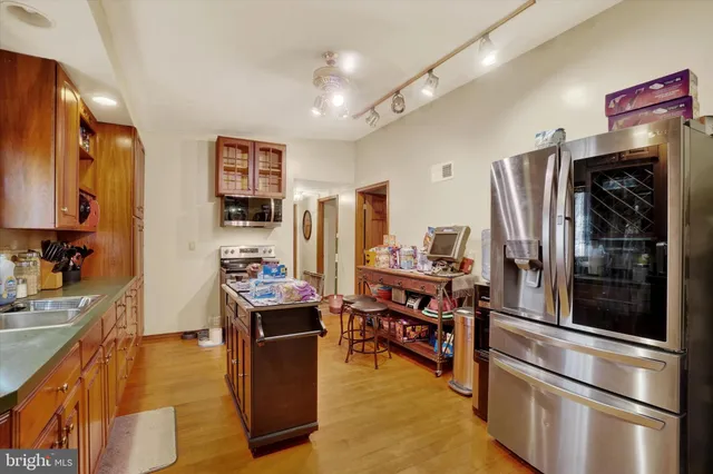 a kitchen with stainless steel appliances kitchen island granite countertop a refrigerator and a stove