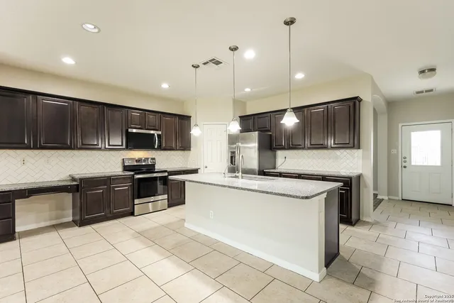 a kitchen with stainless steel appliances granite countertop a stove top oven a sink a microwave and a refrigerator