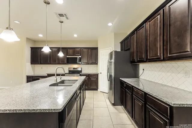 a kitchen with stainless steel appliances granite countertop a sink a stove and a refrigerator