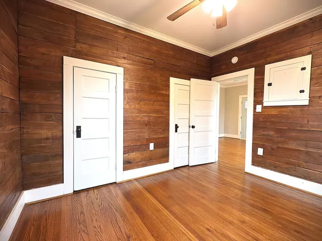 a view of an empty room with wooden floor and a window