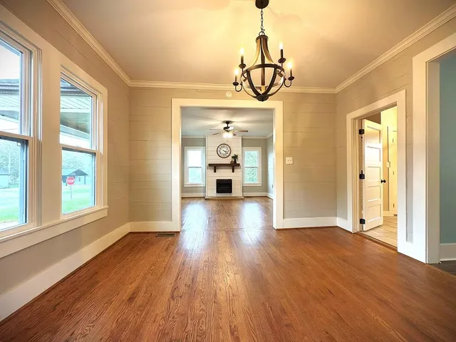 a view of a livingroom with a fireplace a ceiling fan and wooden floor