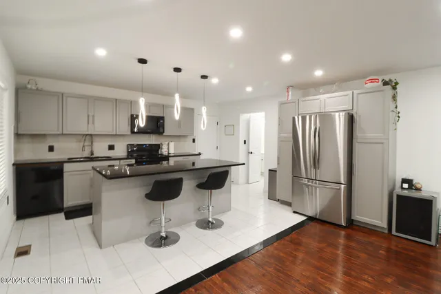 a kitchen with stainless steel appliances granite countertop a sink a stove a refrigerator a center island and chairs