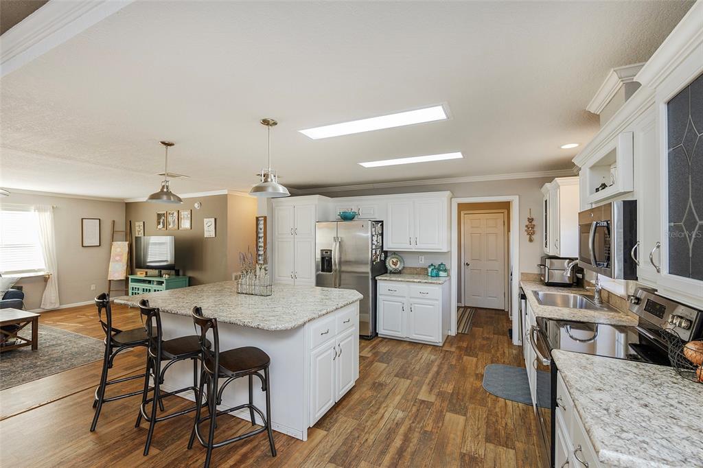 2100 East Kicklighter Road Lake Helen, FL 32744 - Photo 6 of 61 a large kitchen with a table chairs refrigerator and wooden floor