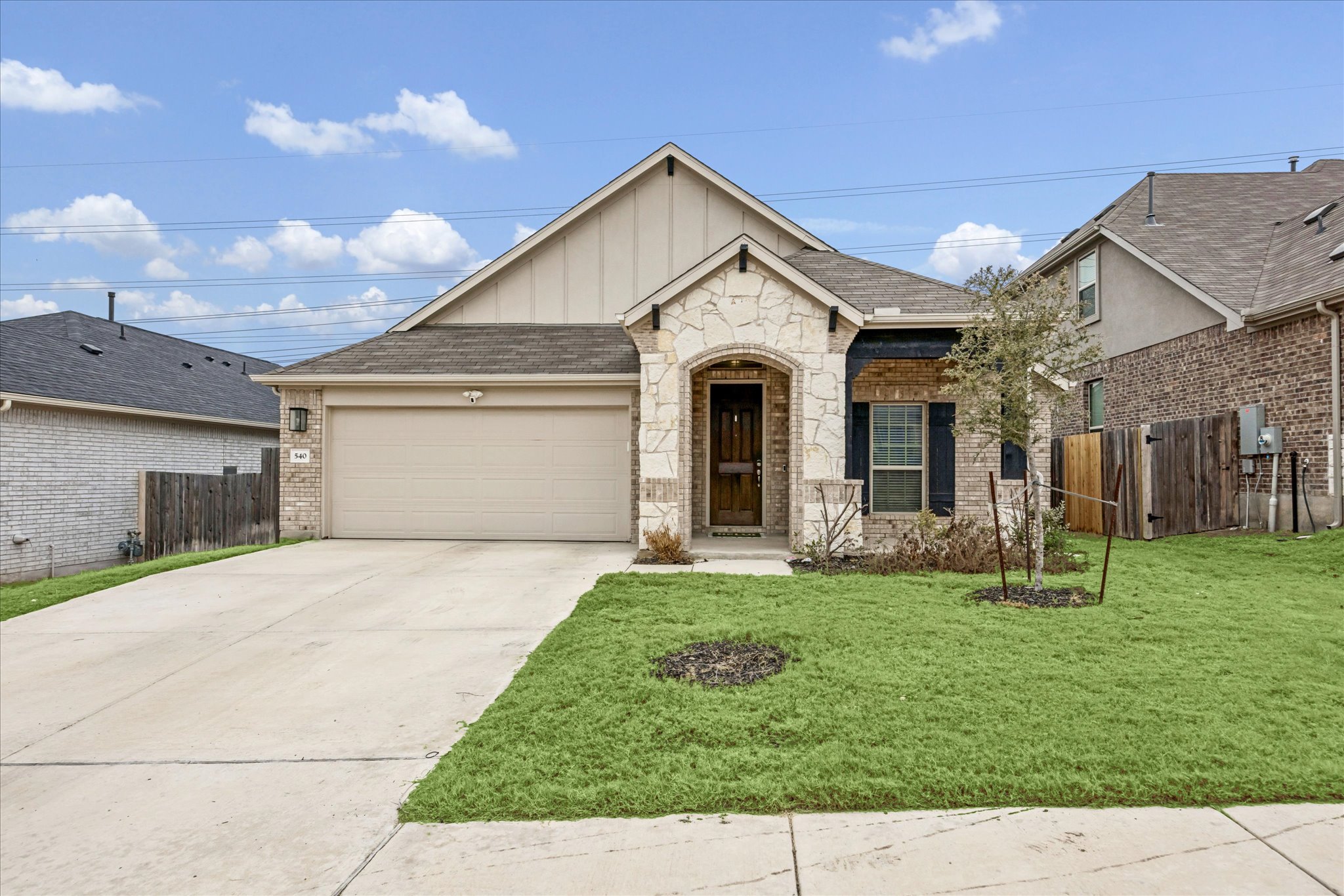540 Sugar Cane Buda, TX 78610 - Photo 1 of 11 View of front facade featuring board and batten siding, a garage, concrete driveway, and brick siding