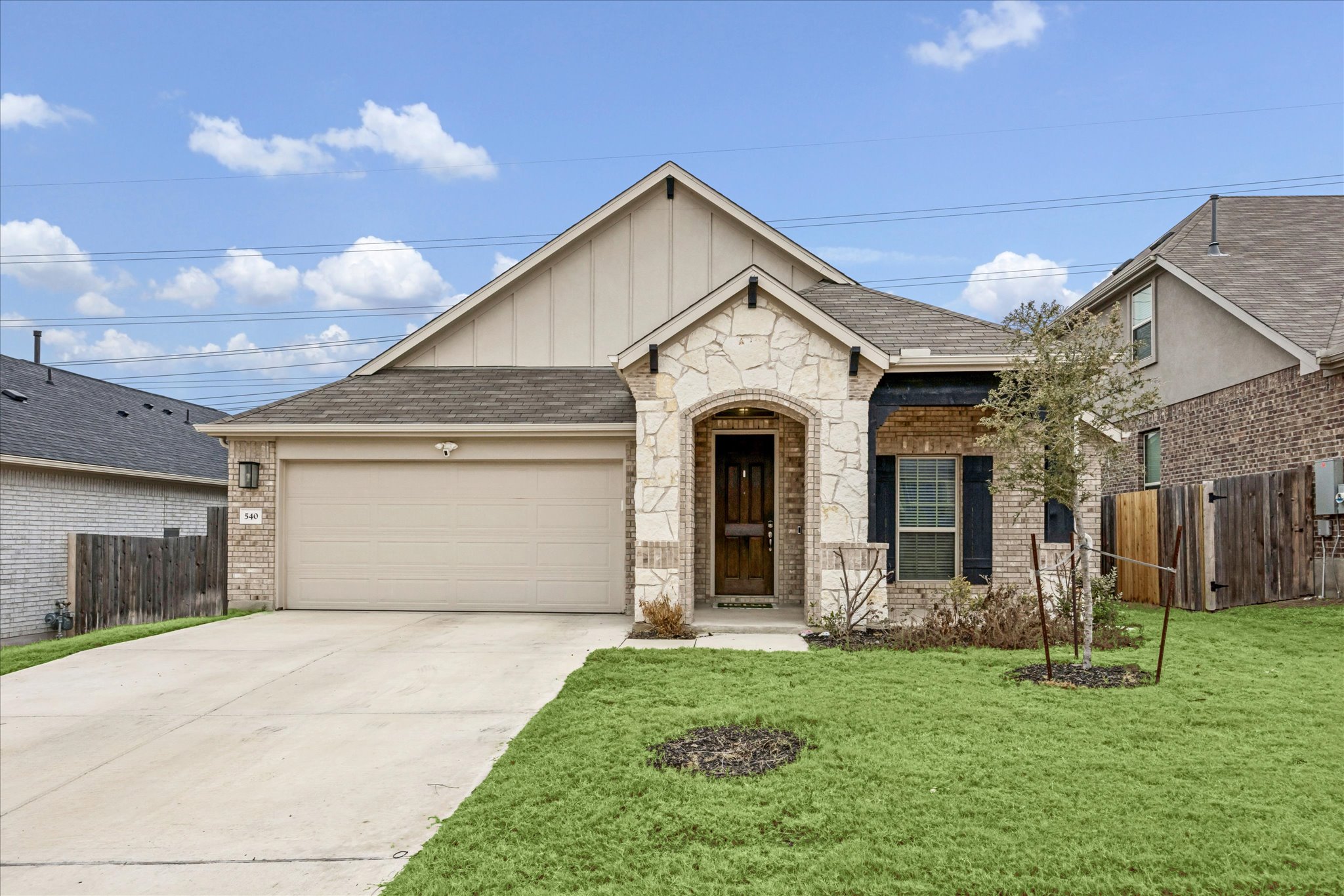 540 Sugar Cane Buda, TX 78610 - Photo 2 of 11 View of front of property featuring a garage, driveway, board and batten siding, brick siding, and stone siding