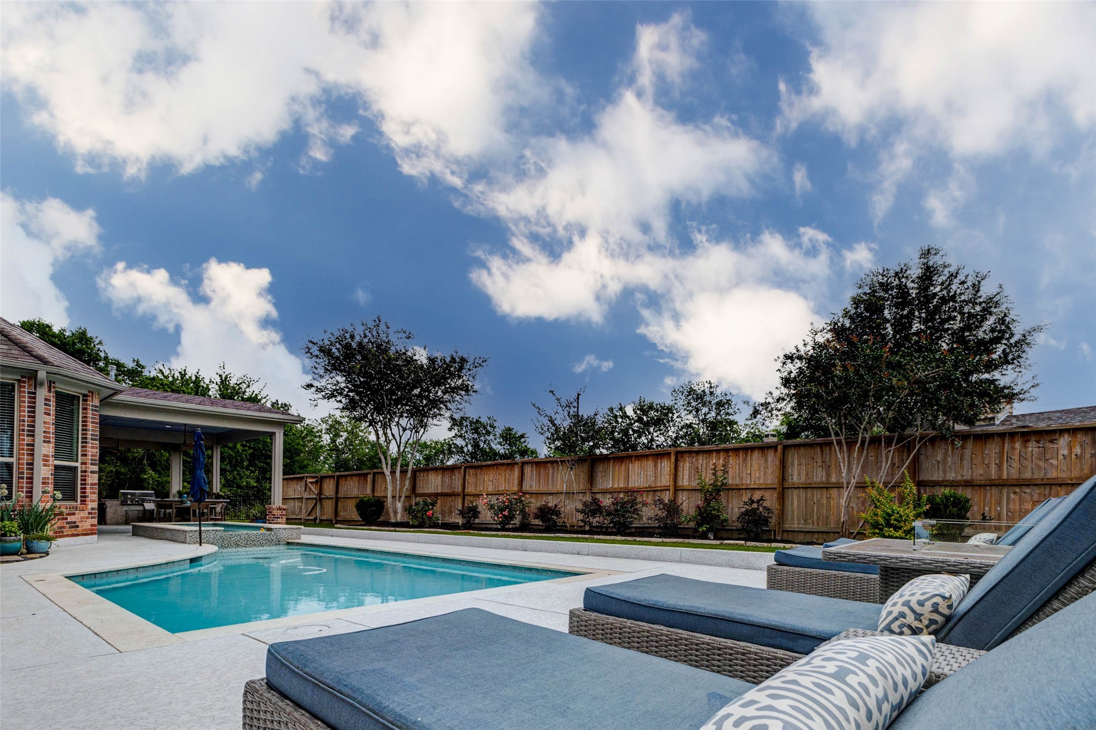 29903 Spring Side Court Fulshear, TX 77406 - Photo 43 of 50 Your private backyard retreat was designed for entertaining and relaxation alike, complete with a sparkling pool, expansive decking for lounge seating, manicured landscaping, and plenty of greenspace to enjoy the outdoors.