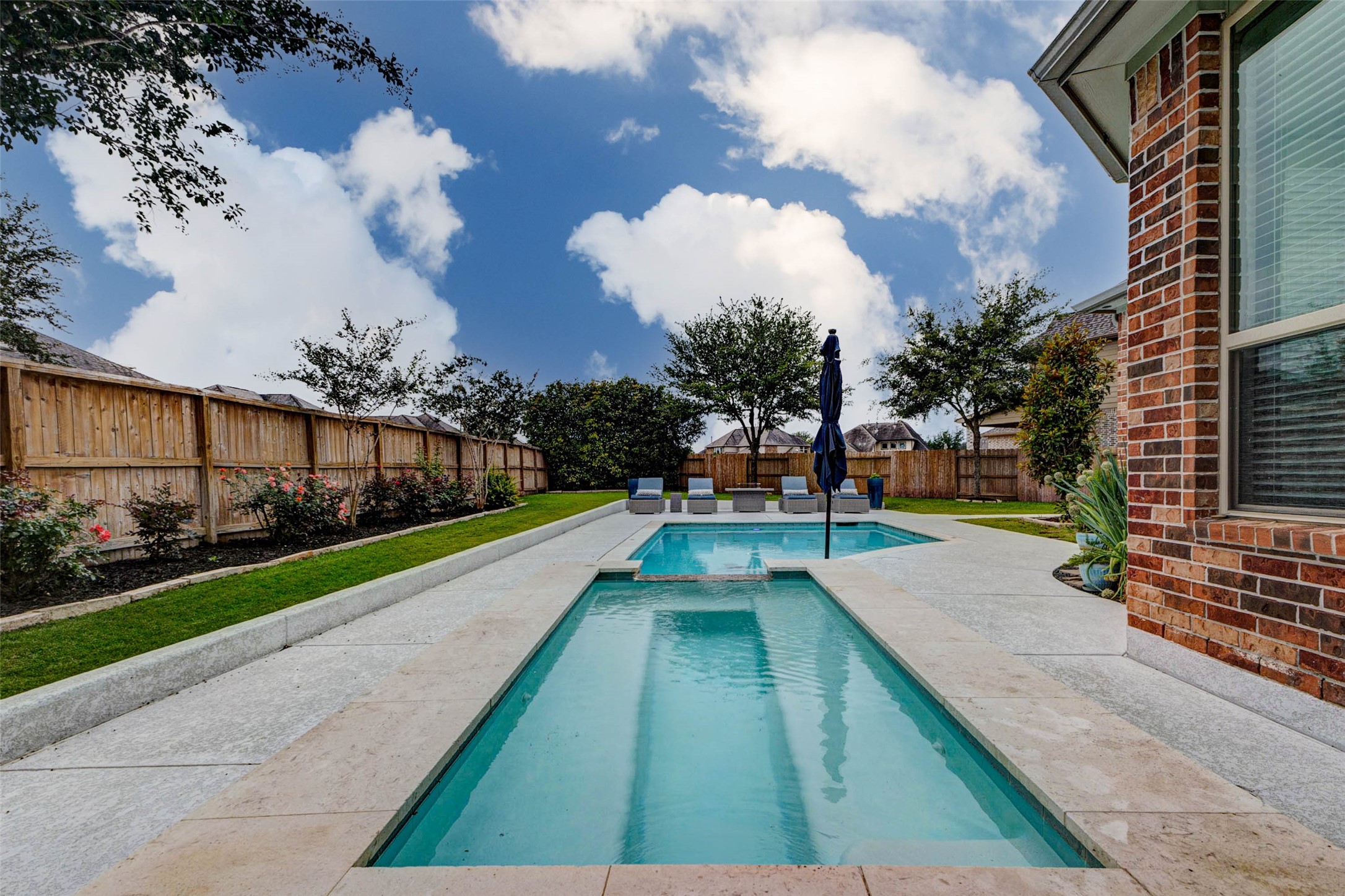 29903 Spring Side Court Fulshear, TX 77406 - Photo 44 of 50 The in-ground gunite pool and spa, built in 2020, create a true backyard oasis complete with beautiful neutral-toned coping, expansive decking, and plenty of room to relax or entertain outdoors.