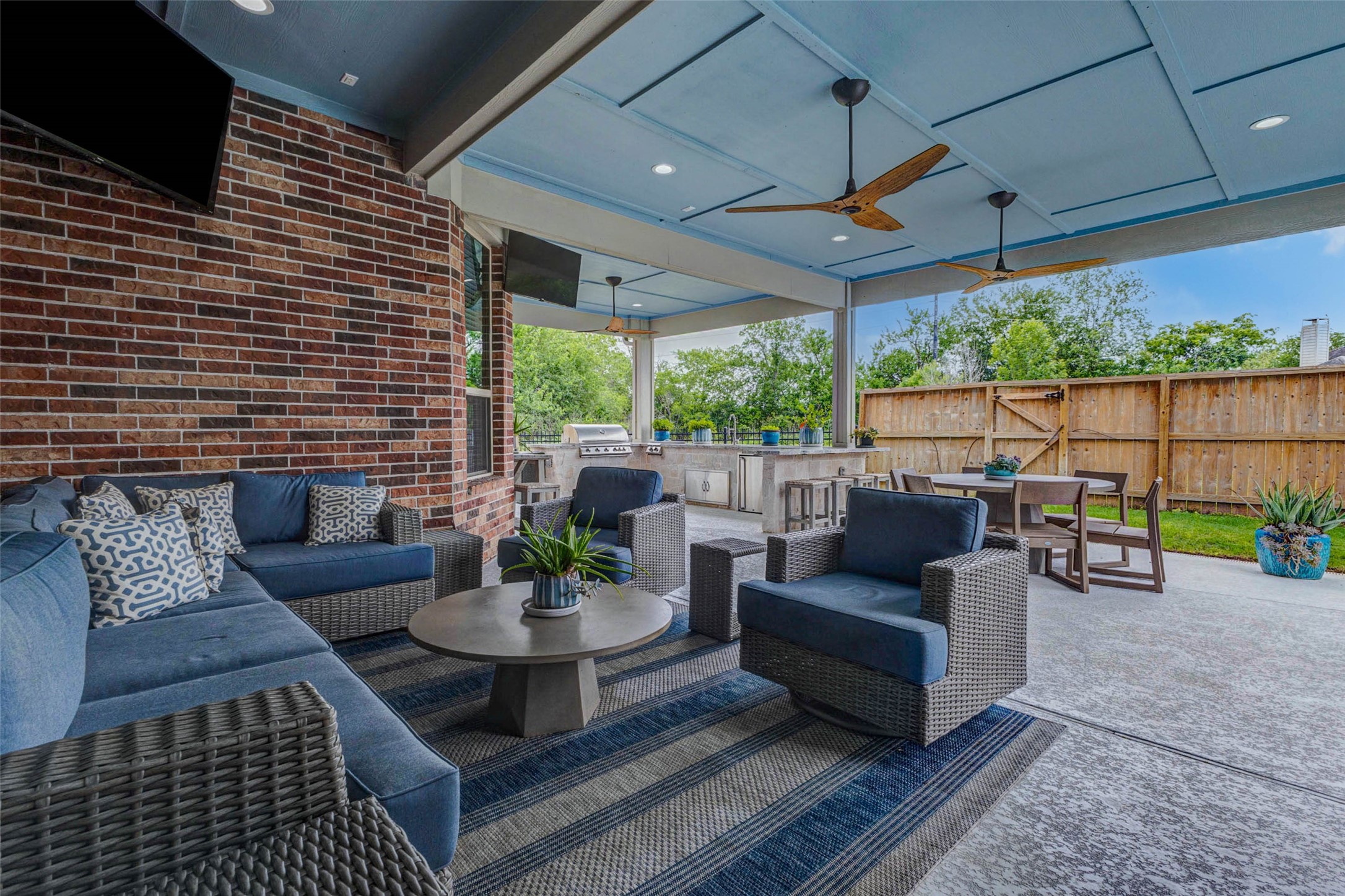 29903 Spring Side Court Fulshear, TX 77406 - Photo 45 of 50 Designed for year-round entertaining, this expansive covered patio features multiple seating areas, ceiling detail with statement fans, and a fully equipped outdoor kitchen overlooking the pool and backyard.