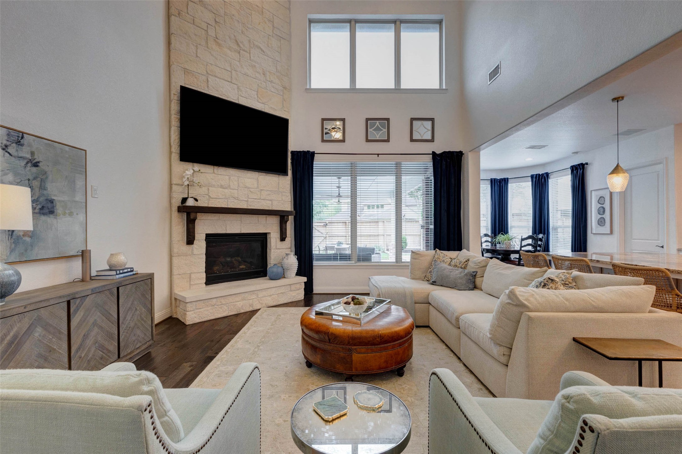 29903 Spring Side Court Fulshear, TX 77406 - Photo 8 of 50 The impressive living room is anchored by a stunning floor to ceiling stone fireplace that extends to the soaring two story ceiling. Expansive windows fill the space with natural light while the open layout creates an inviting atmosphere that is ideal for both everyday living and entertaining.