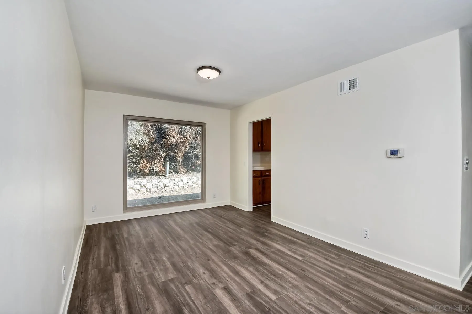 13541 Willow Run Road Poway, CA 92064 - Photo 9 of 40 a view of an empty room with wooden floor and a window