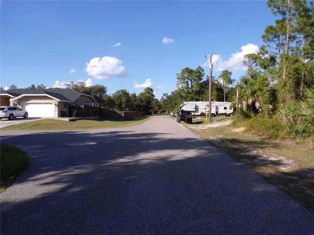 a view of a street with a yard and trees