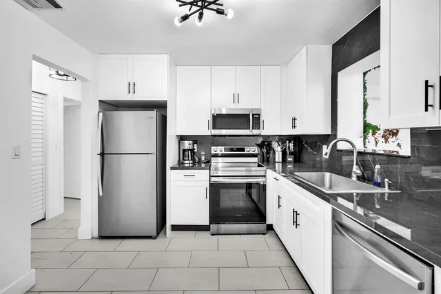 a kitchen with a refrigerator sink and white cabinets