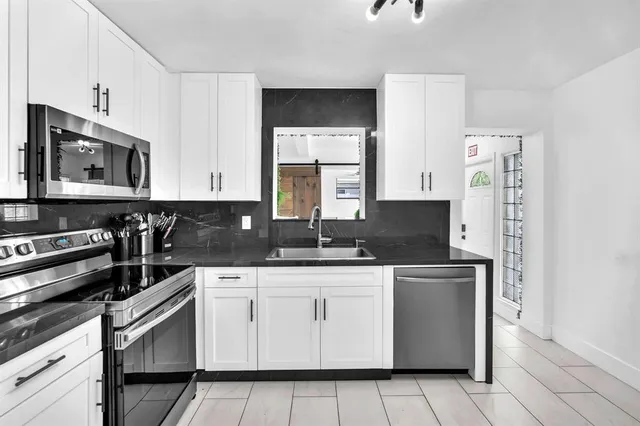 a kitchen with granite countertop white cabinets white stainless steel appliances and sink