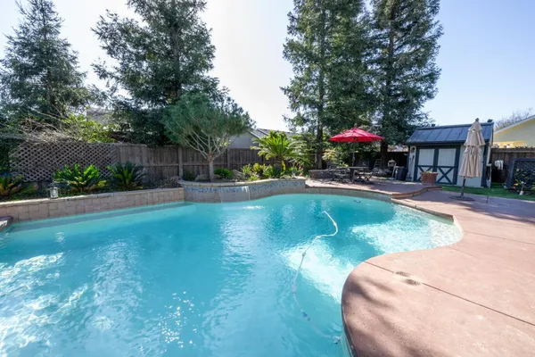 a swimming pool with outdoor view and trees in the background