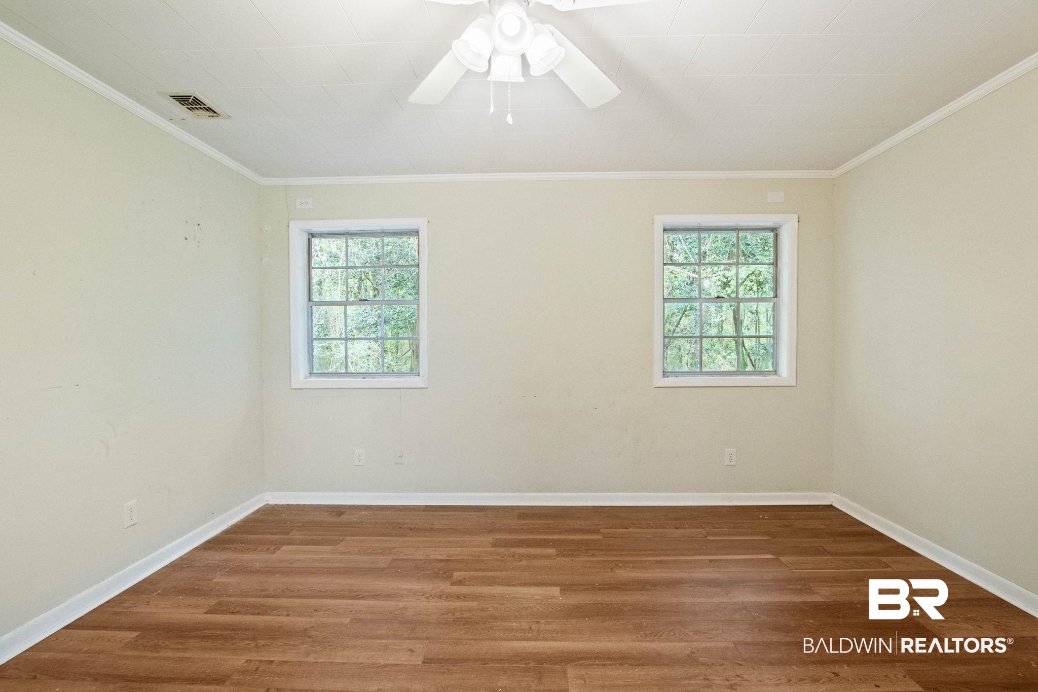 384 Old Bratt Road Atmore, AL 36502 - Photo 37 of 64 Room featuring two windows, wood-finish flooring, light-toned walls, white crown molding, and a ceiling fan