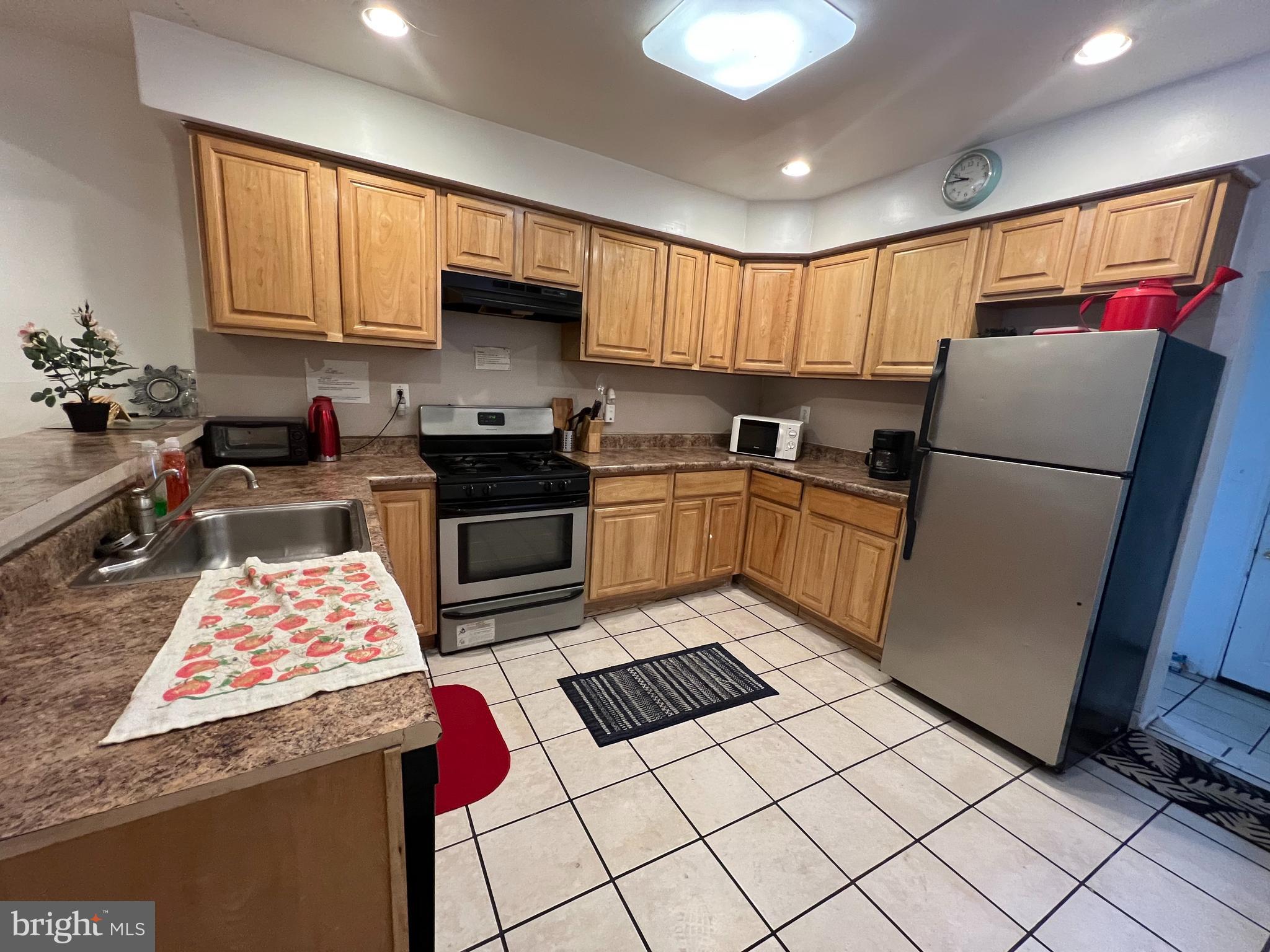 a kitchen with granite countertop stainless steel appliances a stove a sink dishwasher a refrigerator and cabinets with wooden floor
