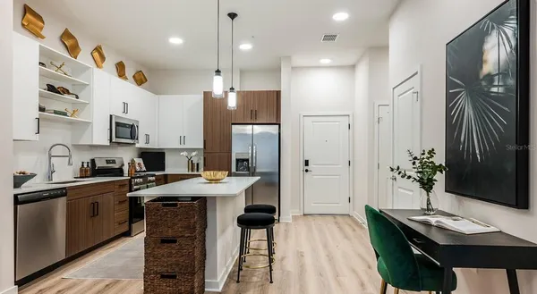 a kitchen with stainless steel appliances kitchen island granite countertop a refrigerator a sink dishwasher a stove and a dining table with wooden floor