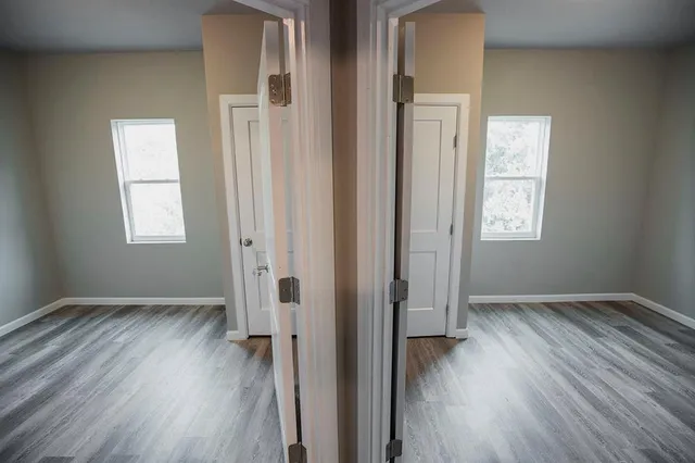 an empty room with wooden floor and windows