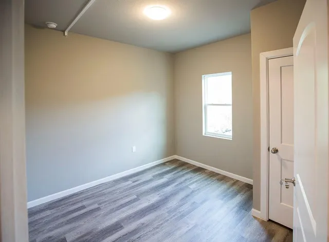 an empty room with wooden floor and a window
