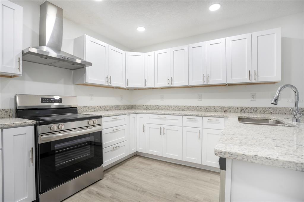 8448 Balm Street Weeki Wachee, FL 34607 - Photo 14 of 44 a kitchen with granite countertop white cabinets and a stove