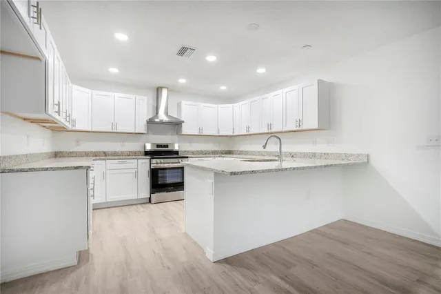 a kitchen with granite countertop wooden floors stainless steel appliances and white cabinets