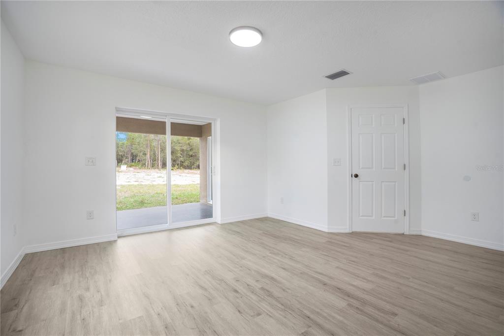 8448 Balm Street Weeki Wachee, FL 34607 - Photo 19 of 44 a view of an empty room with wooden floor and a window