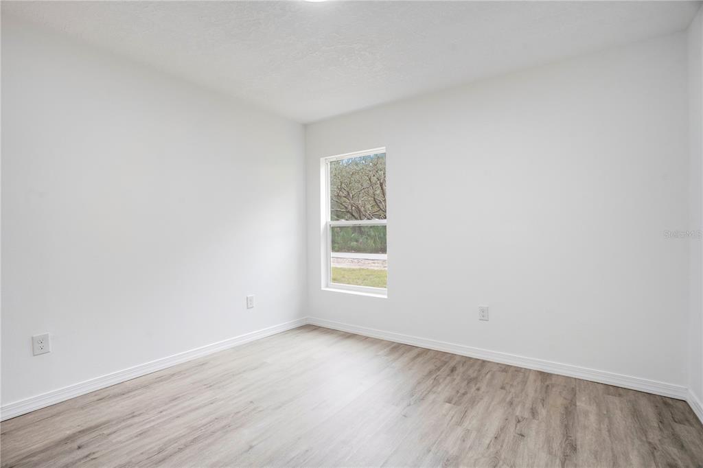 8448 Balm Street Weeki Wachee, FL 34607 - Photo 22 of 44 an empty room with wooden floor and window