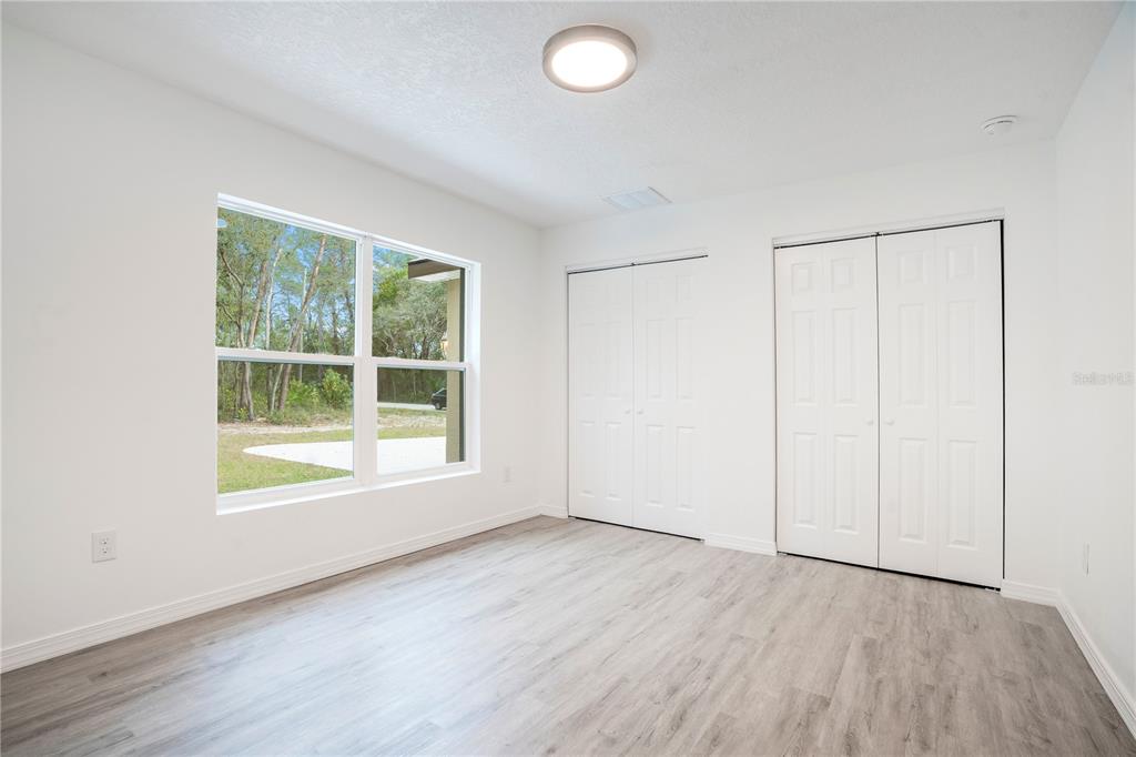 8448 Balm Street Weeki Wachee, FL 34607 - Photo 27 of 44 an empty room with wooden floor and windows