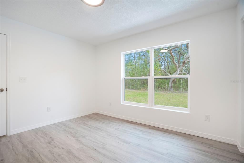 8448 Balm Street Weeki Wachee, FL 34607 - Photo 28 of 44 an empty room with wooden floor and windows