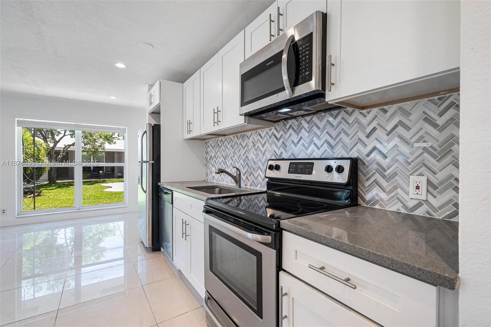 2201 Northeast 14th Avenue, Unit 9 Wilton Manors, FL 33305 - Photo 22 of 30 a kitchen with stainless steel appliances granite countertop a stove a microwave and a sink