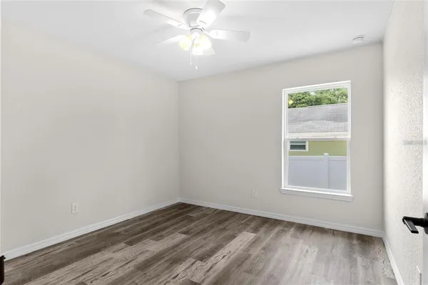 an empty room with a window and a ceiling fan