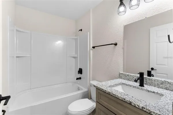 a bathroom with a granite countertop sink toilet tub and shower