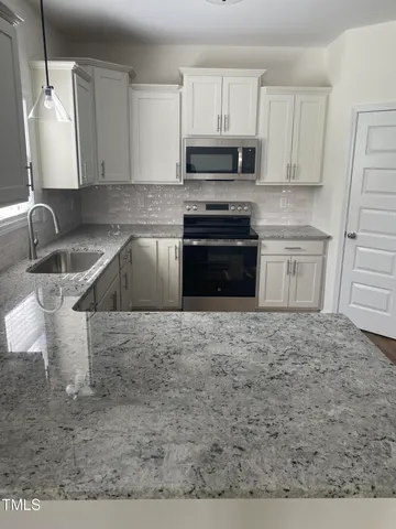 a kitchen with granite countertop a stove sink and cabinets