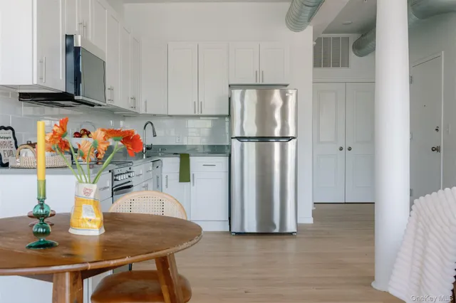 a kitchen with stainless steel appliances granite countertop a refrigerator a stove a sink dishwasher and microwave with wooden floor