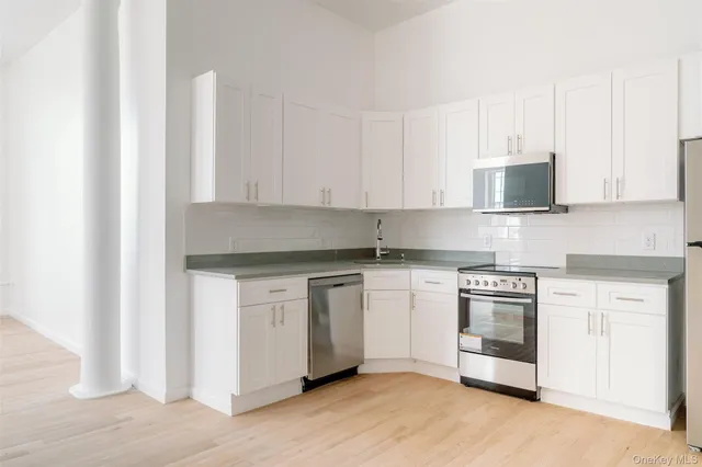 a kitchen with stainless steel appliances granite countertop a stove a sink and white cabinets
