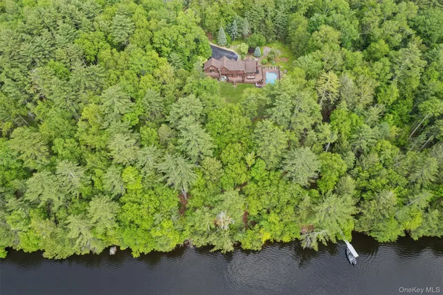 a view of a lake with a bench and trees in the background