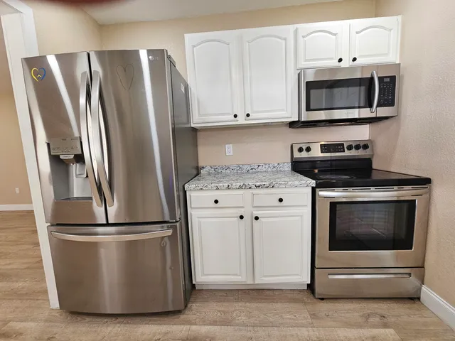 a kitchen with stainless steel appliances white cabinets white stove a microwave and a refrigerator