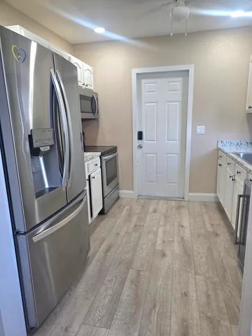 a view of a refrigerator in kitchen and an empty room