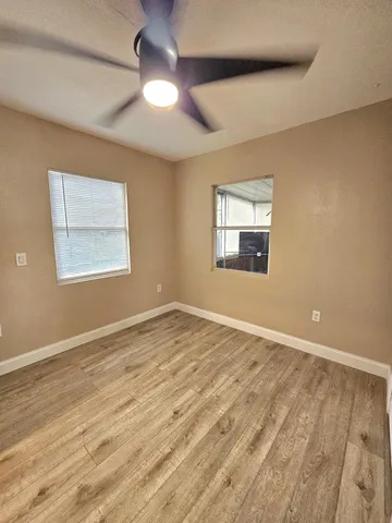 an empty room with wooden floor chandelier and windows