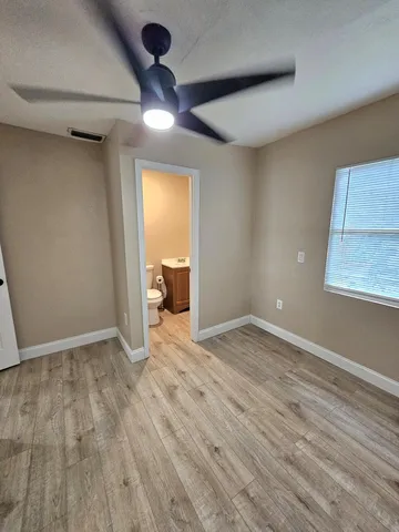 a view of empty room with wooden floor and fan