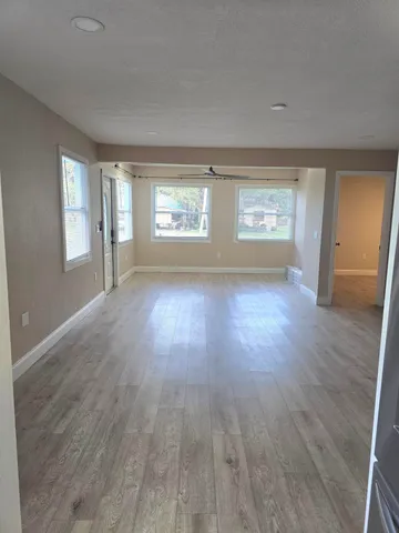 an empty room with wooden floor and windows