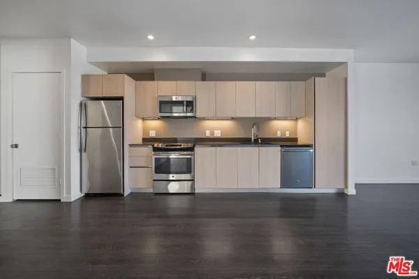 a kitchen with granite countertop a refrigerator and a stove top oven