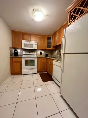 a kitchen with a refrigerator a stove top oven and cabinets