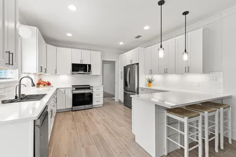 a large kitchen with stainless steel appliances kitchen island granite countertop a stove a sink dishwasher a refrigerator and a oven with wooden floor