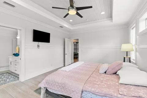 a bedroom with a large bed a flat tv screen and a ceiling fan